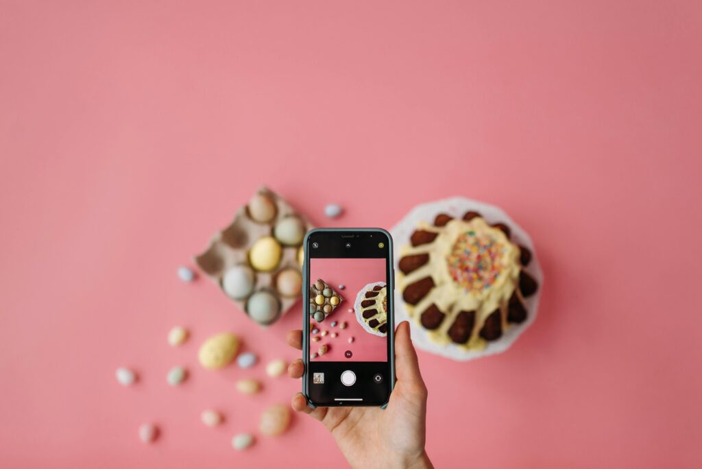 Photo of a Person Taking a Photo of Easter Eggs and a Cake